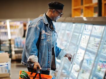 Man grocery shopping opens a refrigerated case.
