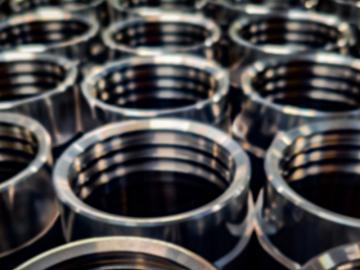 Precision engineering and industrial dark blurred background. A batch of round shiny CNC machined metal parts.