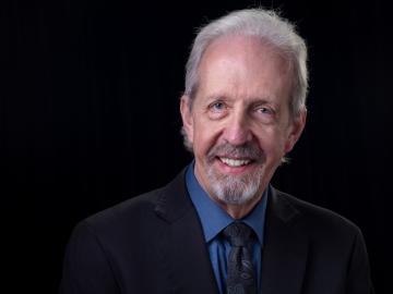 Larry Seiber poses for a photo with a black background