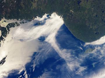 Photo is a high aerial view of lake superior through the clouds