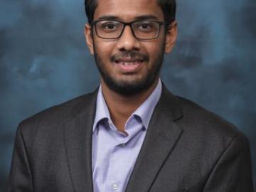 Photo of scientists Arka Daw in a suit with a blue and navy background