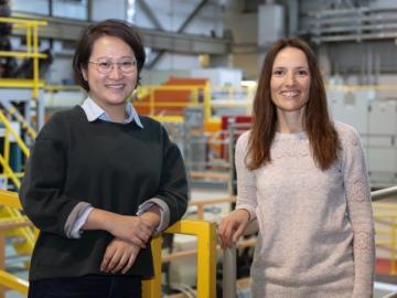 Yue Yuan standing with Flora Meilleur in a railed walkway at the Spallation Neutron Source.