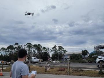 Man is flying drone in hurricane aftermath, holding the controller