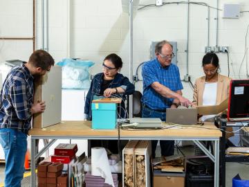 Researchers are looking at computers, working with a bright blue box in the middle of the table
