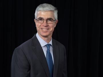 ORNL partnerships director Shaun Gleason is posing in a suit for a photo with a black background