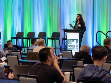 ORNL’s Askin Guler Yigitoglu presents during the 2024 Molten Salt Reactor Workshop in Knoxville with a green and blue background