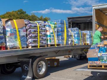 Two semi-trucks filled with supplies for disaster relief, two men loading the trucks