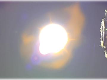 Two cylinders on each side of the photo are pointing to bright glowing orb in the center. 