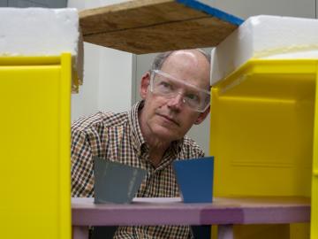 Stephen Killough inspects the metal cones that focus microwaves at a board to detect moisture inside, part of the test setup for a new tool to find moisture in building walls. Credit: Carlos Jones/ORNL, US Dept. of Energy