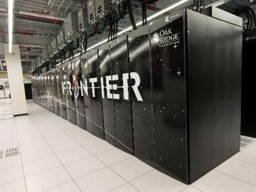 Image of the Frontier supercomputer in black with Frontier spelled out across the cabinets in front. 