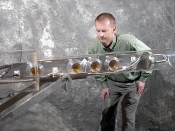ORNL researcher Van Graves examines a transparent cylindrical device he developed and tested at CERN in 2007 to demonstrate that a jet of liquid mercury could serve as a target for a neutrino factory or muon collider.