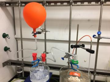 CO2 release by mild heating of the BIG-bicarbonate solid. The released CO2 gas is trapped in the orange balloon, while the released water vapors are trapped by condensation in the ice-cooled U-shaped tube. Credit: Neil J. Williams and Erick Holguin.