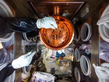 Researchers work on the delicate wiring of a cryostat, which is like a thermos under vacuum that chills the detectors that are the heart of the MAJORANA DEMONSTRATOR. The experiment’s 2 cryostats each house 29 germanium detectors—diodes that are reverse b Researchers work on the delicate wiring of a cryostat, which is like a thermos under vacuum that chills the detectors that are the heart of the MAJORANA DEMONSTRATOR. The experiment’s 2 cryostats each house 29 germanium detectors—diodes that are reverse b