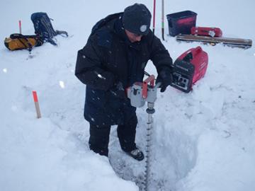 Alex Kholodov (University of Alaska, Fairbanks) uses an electric auger to prepare holes for water wells at NGEE Arctic Sites in Barrow, Alaska