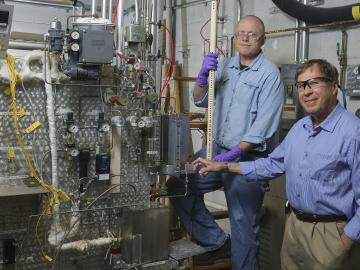 ORNL’s Jim Keiser and Mike Stephens (on stepladder) prepare to install samples in a Keiser rig, a furnace for exposing materials to corrosive gases, crushing pressures and calamitous heat. Image credit: Oak Ridge National Laboratory, U.S. Dept. of Energy;