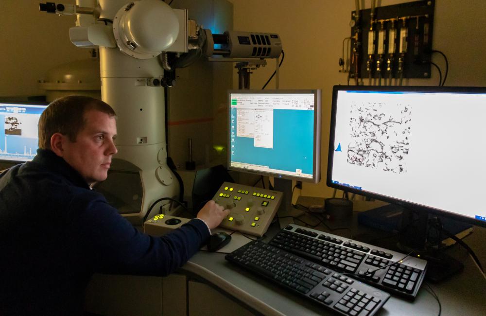 In ORNL’s Low Activation Materials Development and Analysis Laboratory, Field makes use of a transmission electron microscope to examine a sample made with a focused ion beam. He investigates the defects produced in a FeCrAl alloy bombarded with neutrons in HFIR. Credit: Carlos Jones/Oak Ridge National Laboratory, U.S. Dept. of Energy