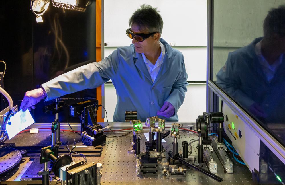 ORNL scientist Adrian Sabau describes components of a laser-interference structuring system that was used to treat aluminum alloy sheets for corrosion protection. Credit: Carlos Jones/ORNL, U.S. Dept. of Energy