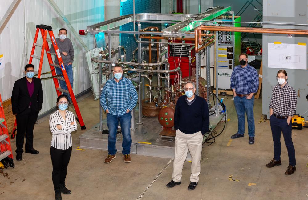 A team of fusion scientists and engineers stand in front of ORNL’s Helium Flow Loop device. From back left to front right: Chris Crawford, Fayaz Rasheed, Joy Fan, Michael Morrow, Charles Kessel, Adam Carroll, and Cody Wiggins. Not pictured: Dennis Youchison and Monica Gehrig. Credit: Carlos Jones/ORNL.