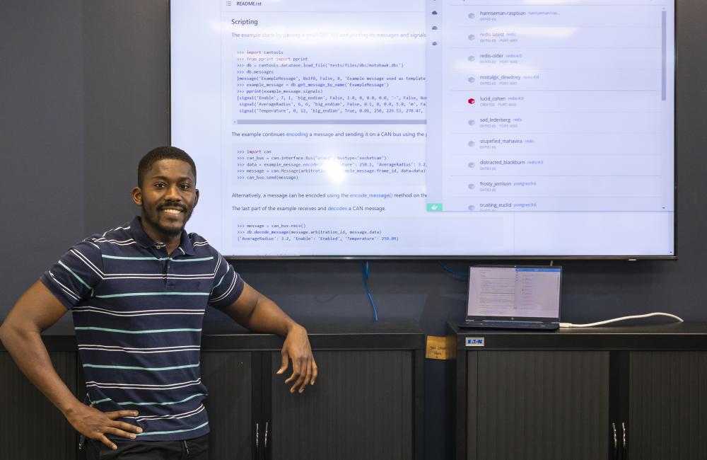 Joel Asiamah poses in front of Github and Docker code.
