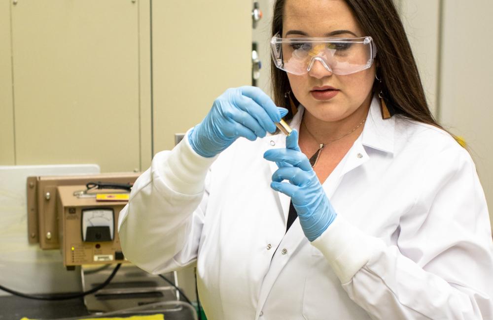 ORNL’s Tyler Spano examines a sample of uranyl nitrate solution that she uses as a precursor to many uranium oxide syntheses.