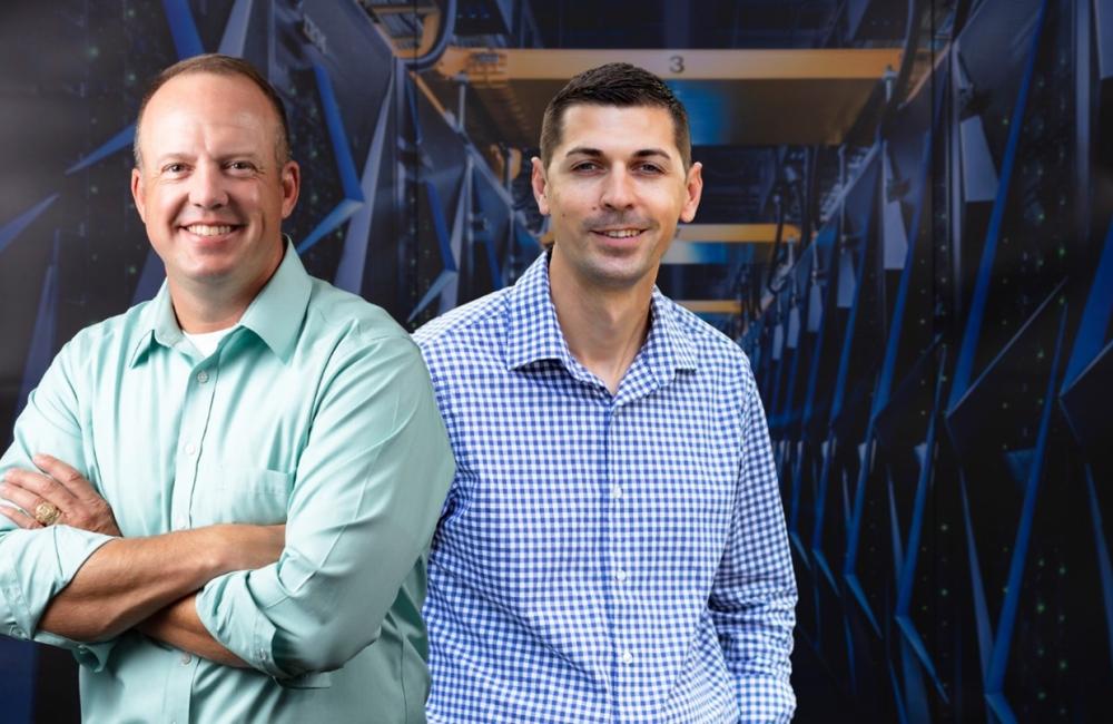 Lt. Col. Brett Cooper and Maj. Matt Postupack pose by ORNL's Summit Supercomputer.