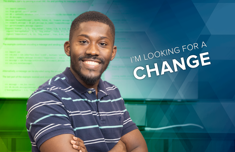 Male researcher standing in front of a screen of code. Words say, "I'm looking for a change"