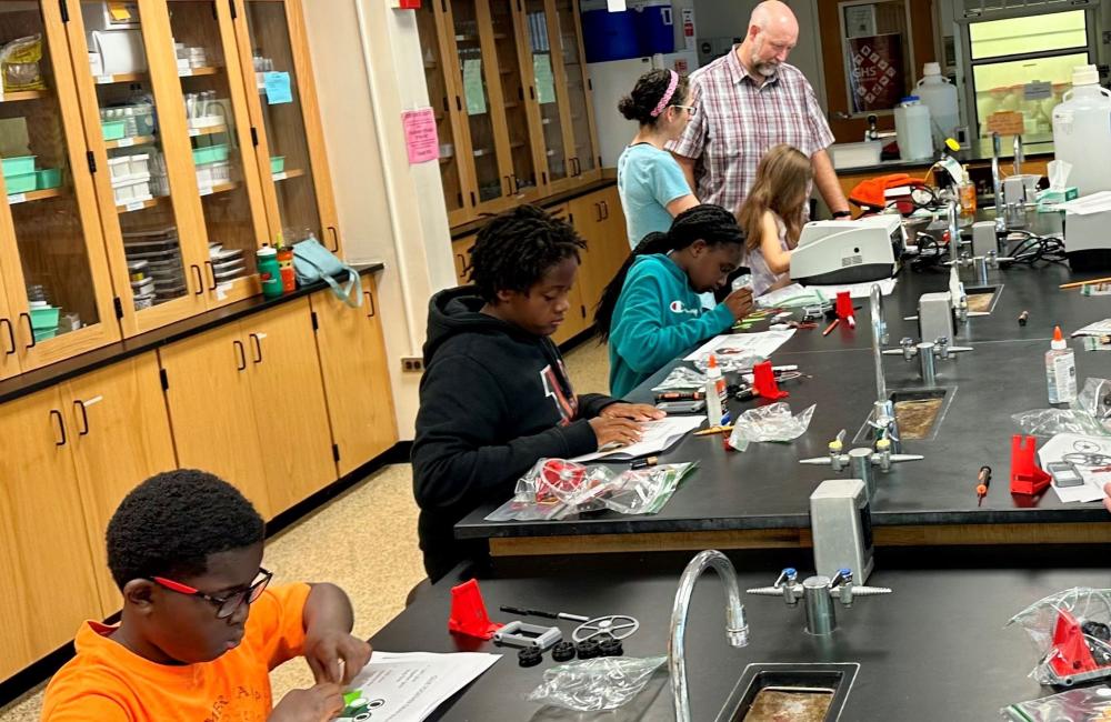 Group of young kids sitting at lab tables. 