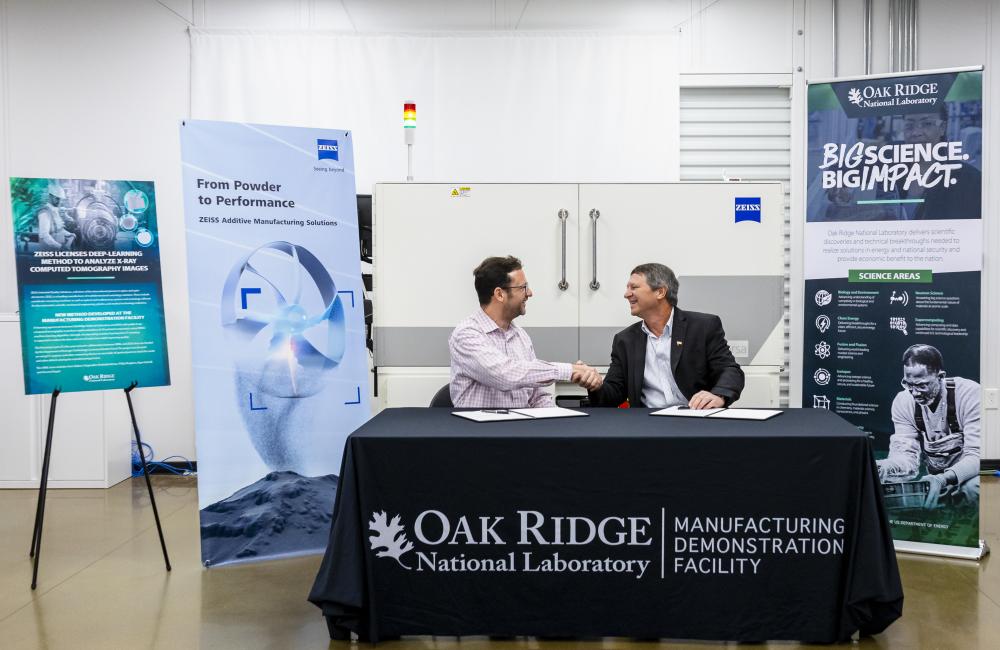 ZEISS Head of Additive Manufacturing Technology Claus Hermannstaedter, left, and ORNL Interim Associate Laboratory Director for Energy Science and Technology Rick Raines sign a licensing agreement that allows ORNL’s machine-learning algorithm, Simurgh, to be used for rapid evaluations of 3D-printed components with industrial X-ray computed tomography, or CT. Using machine learning in CT scanning is expected to reduce the time and cost of inspections of 3D-printed parts by more than ten times.