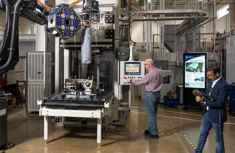 ORNL Composites Innovation staff members David Nuttall, left, and Vipin Kumar use additive manufacturing compression molding to produce a composite-based finished part in minutes. AMCM technology could accelerate decarbonization of the automobile and aerospace industries. Credit: ORNL, U.S. Dept. of Energy