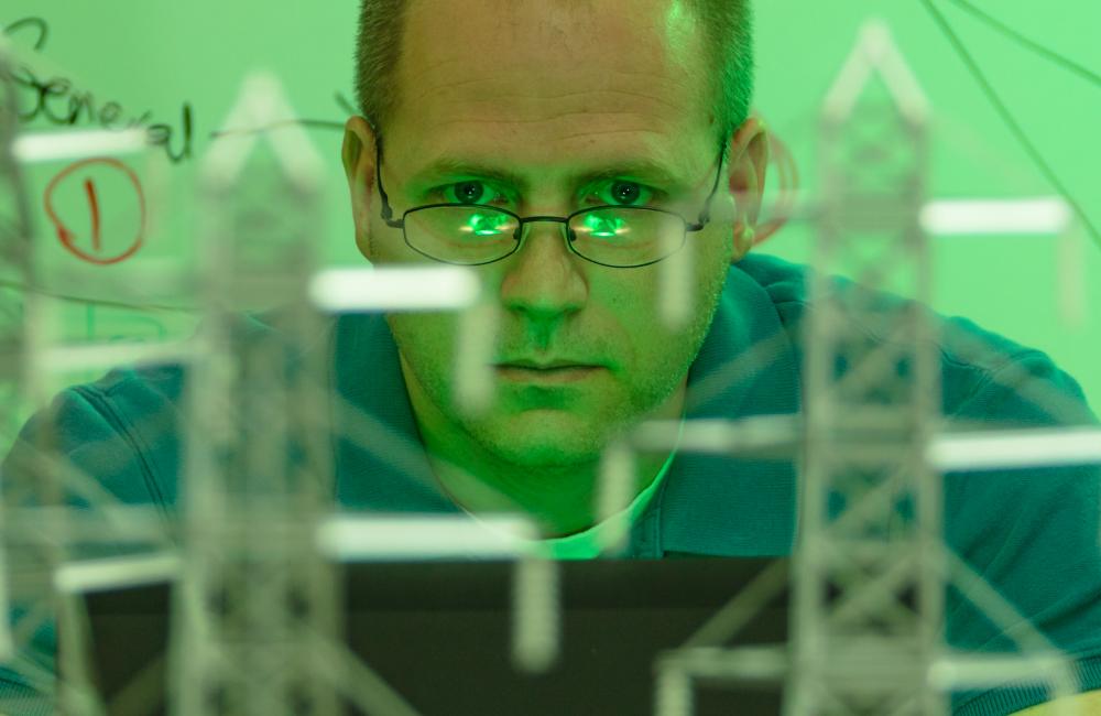 A man looks at a computer with a model of an energy grid in the foreground