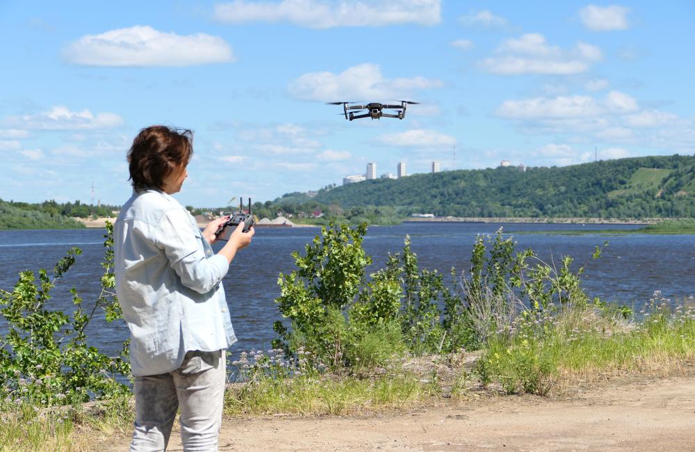 A woman operates a drone near a lake