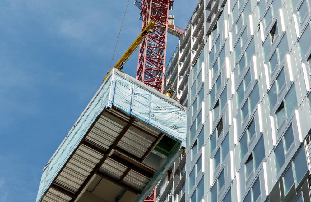 Rectangular box being lifted by a red pully system up the left side of the building