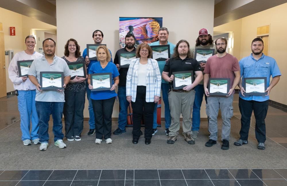 A group photo of technicians and their supervisor after an awards ceremony. 