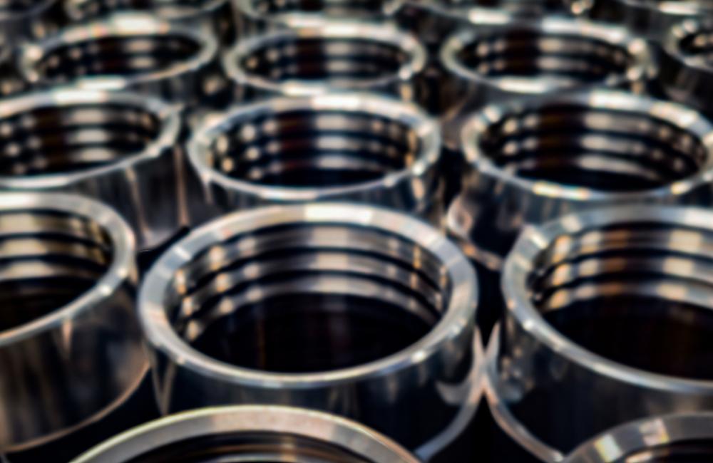 Precision engineering and industrial dark blurred background. A batch of round shiny CNC machined metal parts.