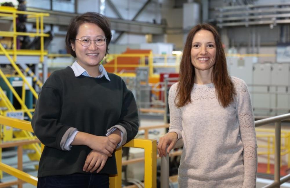 Yue Yuan standing with Flora Meilleur in a railed walkway at the Spallation Neutron Source.