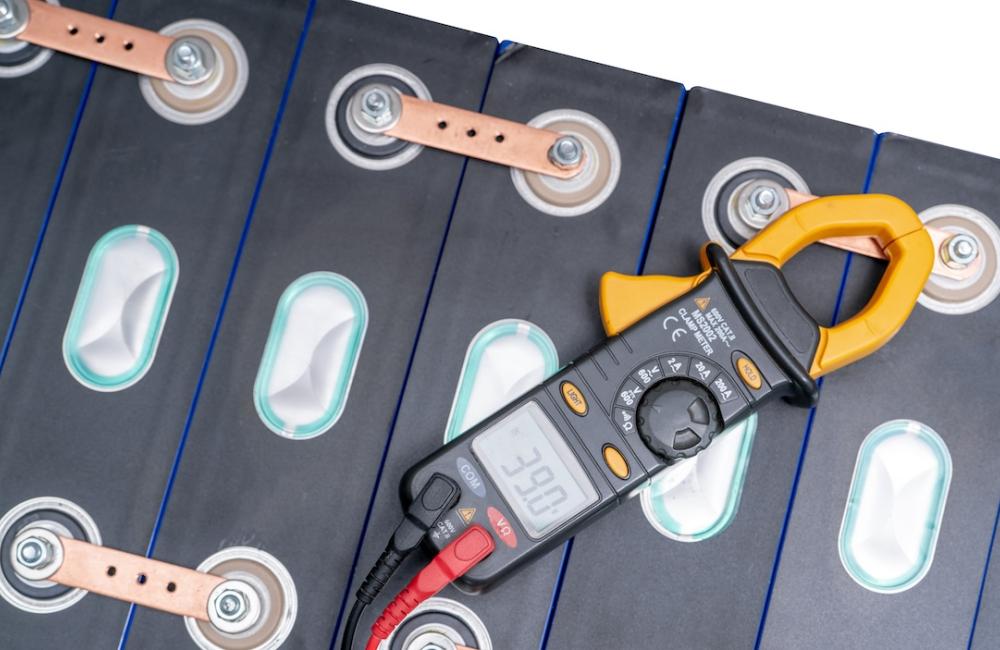 Electric vehicle lithium NMC battery with multimeter measuring volts of electric vehicle battery. Image from Envato.
