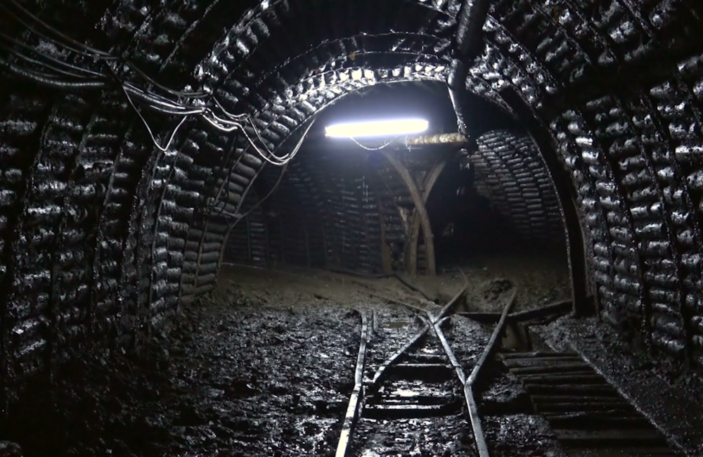 An image of a mine shaft in black and grey, lit by a single light in the middle