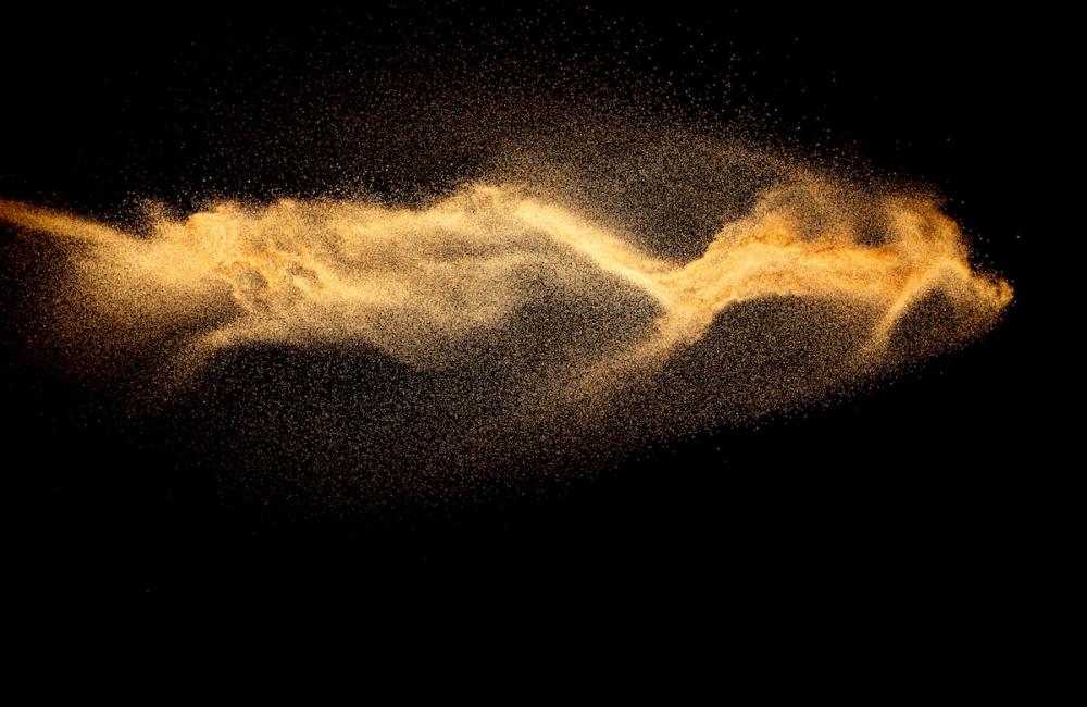 Brown color sand splash against black background. Image from Envato