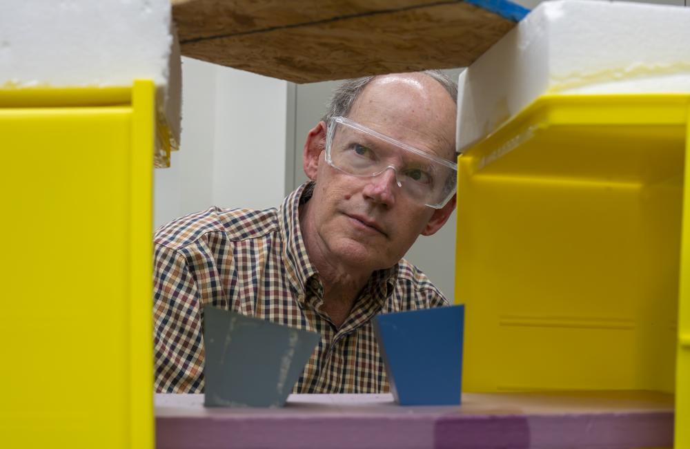 Stephen Killough inspects the metal cones that focus microwaves at a board to detect moisture inside, part of the test setup for a new tool to find moisture in building walls. Credit: Carlos Jones/ORNL, US Dept. of Energy