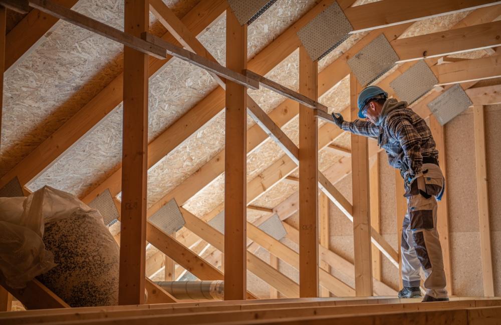 Construction worker checking on wooden attic and roof structure. Image from Envato