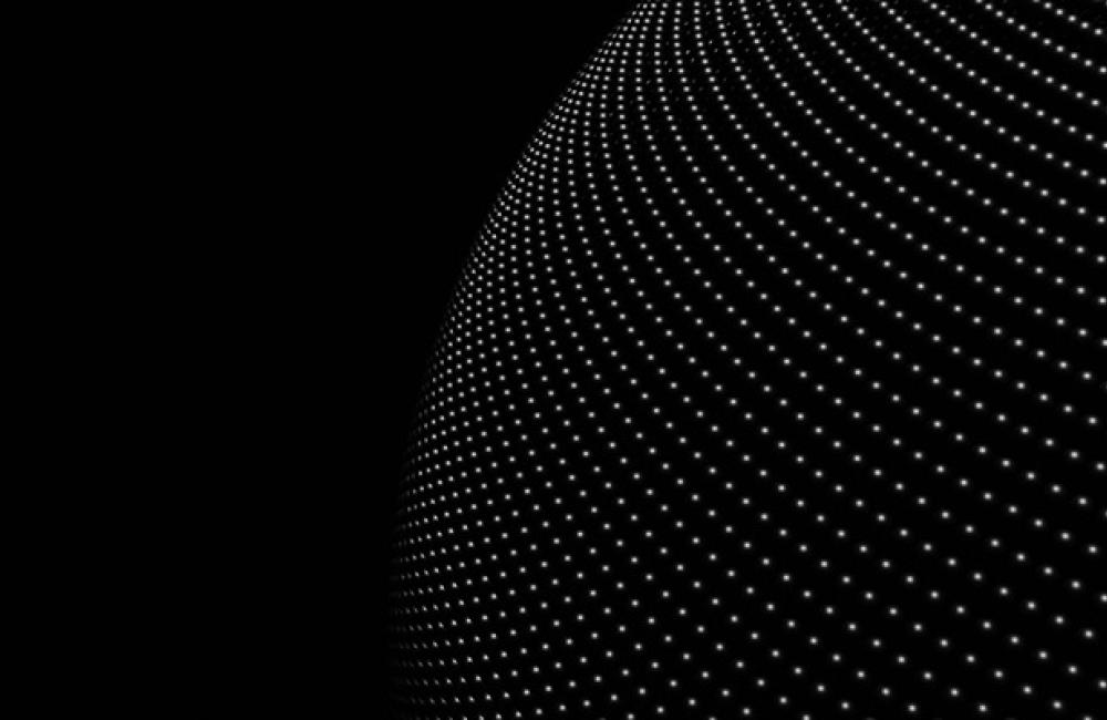 Close-up of a curved surface covered in illuminated dots against a black background, creating a digital wave pattern.