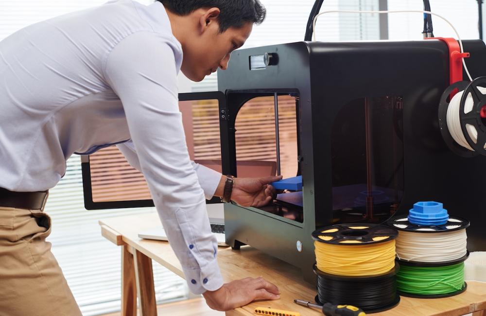 Young male designer creating figures on 3D printer. Image from Envato