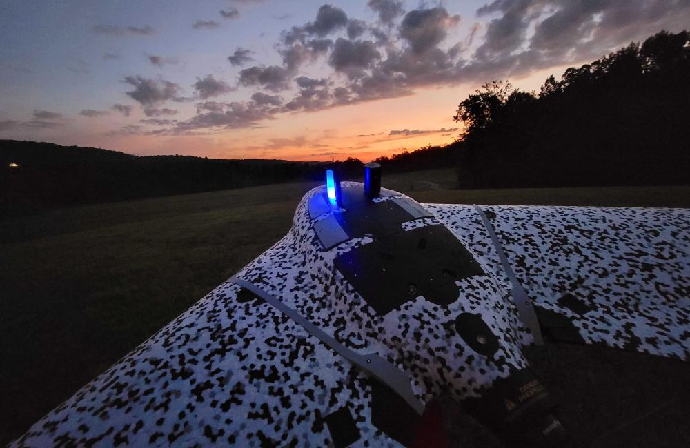 A black-and-white drone about to take off toward a sunrise