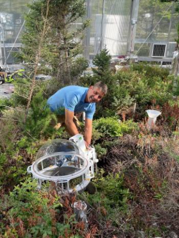 ORNL’s Dave Weston works with instruments at the SPRUCE experiment that measure methane and carbon dioxide emissions from moss and smalls shrubs. Credit: Kyle Pearson/ORNL, U.S. Dept. of Energy