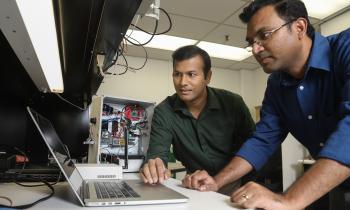 Two men look at a computer in a lab space