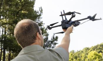 An over-the-shoulder view of a man launching a quadcopter drone from his hand