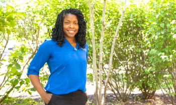 A woman stands in front of trees