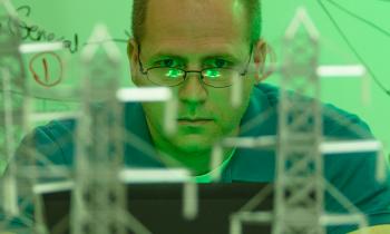 A man looks at a computer with a model of an energy grid in the foreground