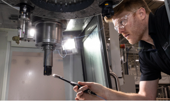 researcher with safety glasses uses tool to adjust machine