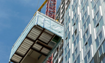tall building with a crane lifting building materials next to it